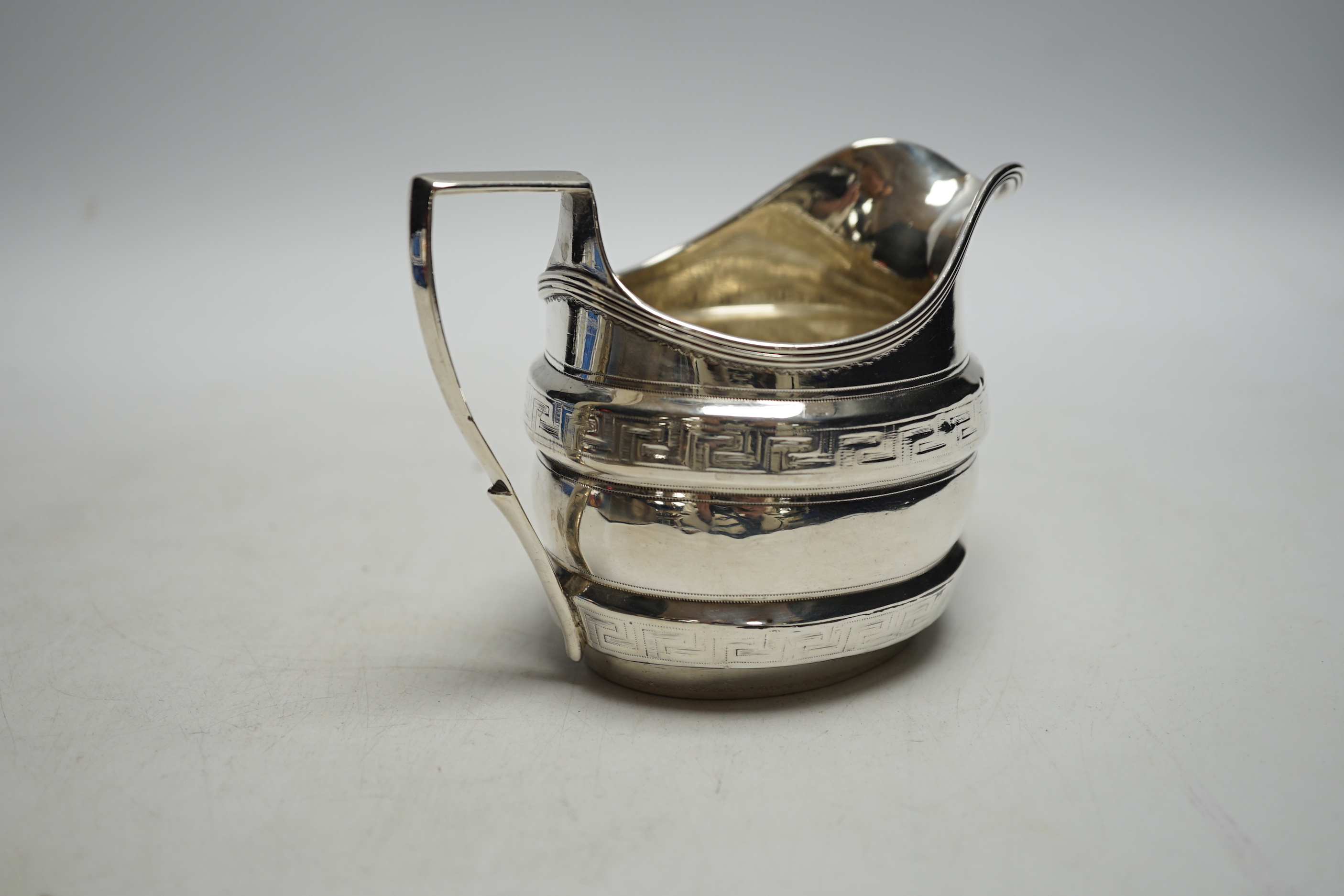 A George III silver helmet shaped cream jug, with engraved key pattern band, London 1804, 9cm. (a.f.)